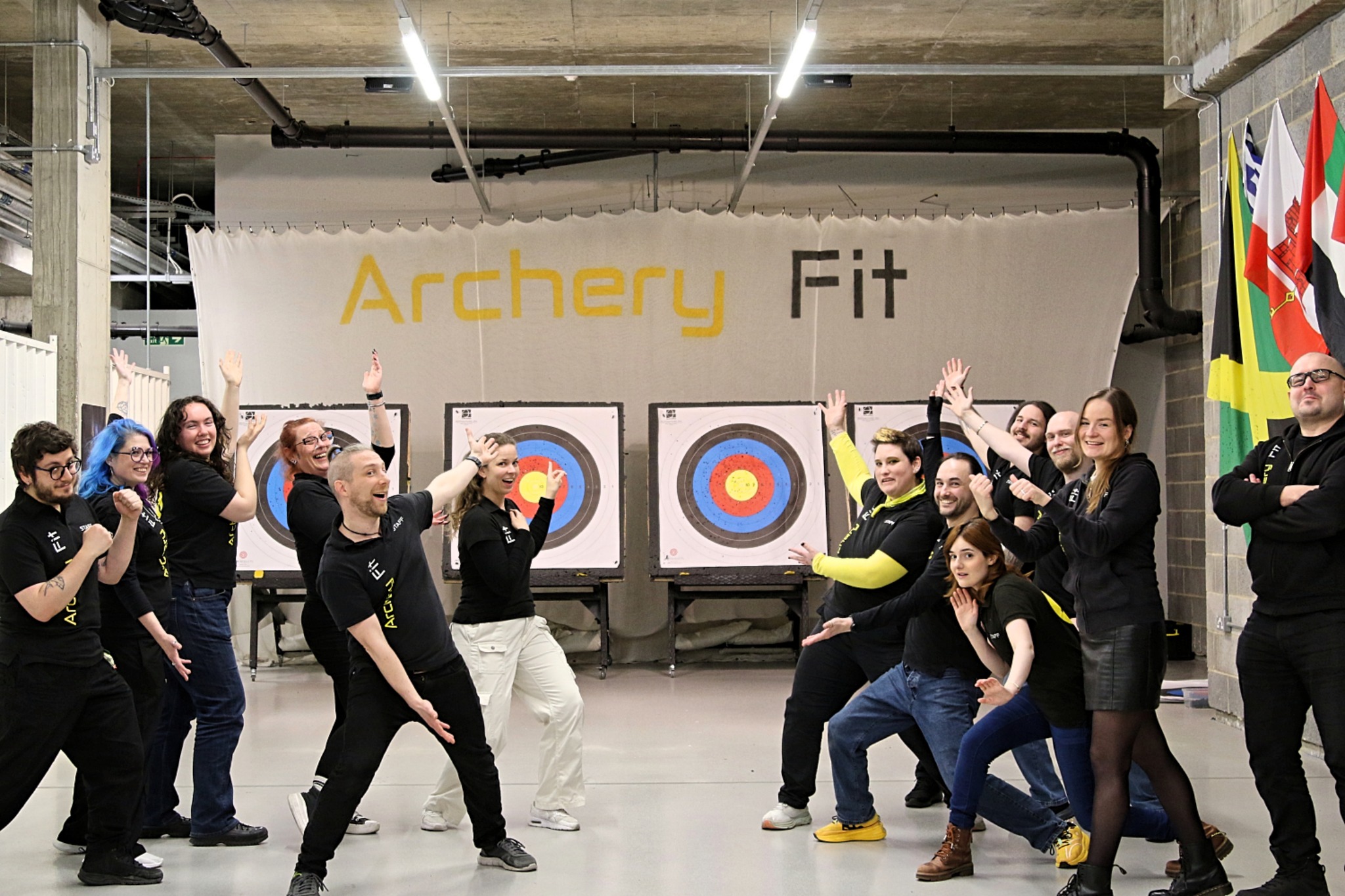 The Archery Fit coaching team posing in front of the indoor range targets